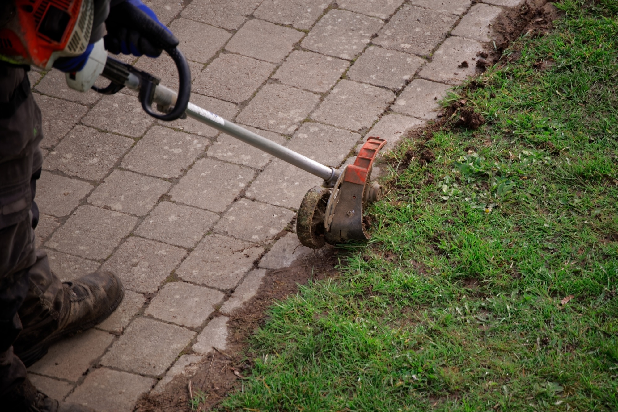 Worker uses edge trimmer at the pathway